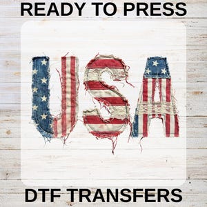 May include: A design spelling "USA" in red, white, and blue, mimicking the American flag. The letters are crafted from distressed fabric, giving a vintage feel. The words "READY TO PRESS" and "DTF TRANSFERS" are displayed above and below the letters.