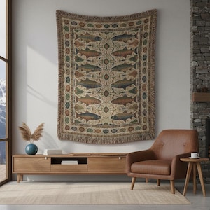 May include: A woven tapestry with a fish pattern in shades of brown, green, and blue hangs on a white wall. The tapestry has a fringed border. A wooden media console, a leather armchair, and a small side table are in the room.