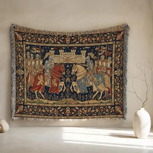 May include: A tapestry depicting a medieval battle scene with knights on horseback, a castle, and soldiers. The tapestry features a dark blue background with ornate floral borders and fringe.