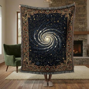 May include: A dark blue woven throw blanket featuring a spiral galaxy design with constellations and planets. The blanket has a decorative border with fringe edges. The color palette includes shades of blue, gold, and white.