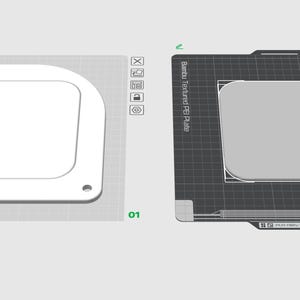 May include: Two 3D-rendered models of a square-shaped object with rounded corners. One is white, the other is gray, both on a gray surface. The white model has a cutout and holes. The gray model is on a black surface with text.
