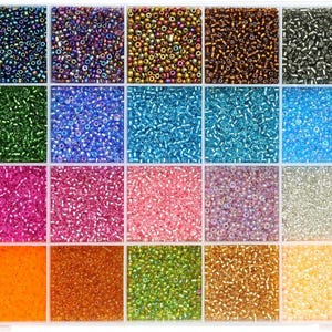 May include: A rectangular clear plastic storage container divided into twenty-eight individual square compartments, each filled with small seed beads in a wide variety of colors including black, blue, green, pink, orange, yellow, and white.