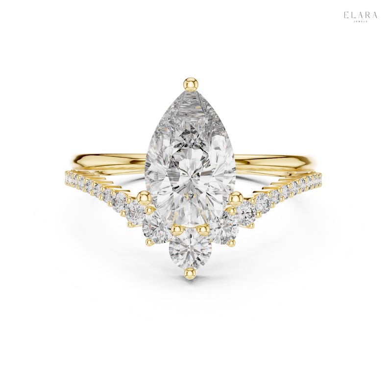 May include: A gold engagement ring with a pear-shaped diamond center stone. The ring features a delicate band and a curved row of smaller diamonds. The ring is set against a white background.