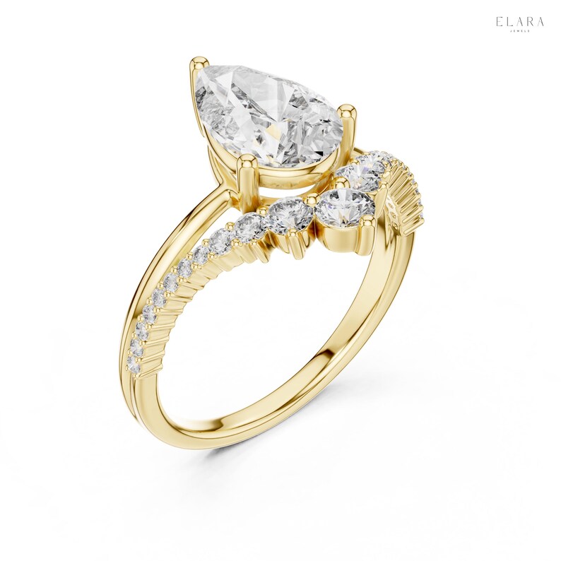 May include: A gold engagement ring with a pear-shaped diamond center stone. The ring features a split shank design with smaller diamonds set along the band and a curved row of diamonds accenting the center stone. The ring is set against a white background.