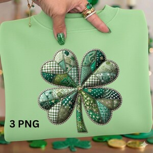 May include: A pale green sweatshirt with a four-leaf clover design. The clover is made from various green patterned fabrics and has a sparkling border. The text "3 PNG" is printed in black at the bottom left of the sweatshirt.