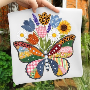 Op de afbeelding: Wit vierkant kussen met een kleurrijke vlinder met patchwork vleugels en een boeket bloemen. De vlinder heeft strass accenten en is omgeven door madeliefjes, zonnebloemen en diverse tulp- en lavendelontwerpen. Het kussen wordt door een hand vastgehouden.