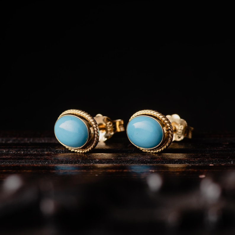 May include: A pair of gold oval earrings with blue turquoise stones.