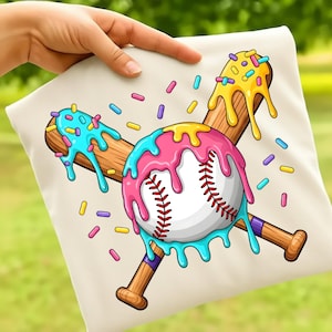 May include: A cream-colored pillow with a baseball-themed design. The design features a baseball with pink, blue, and yellow dripping icing, crossed with two wooden baseball bats. Colorful sprinkles are scattered around the design.