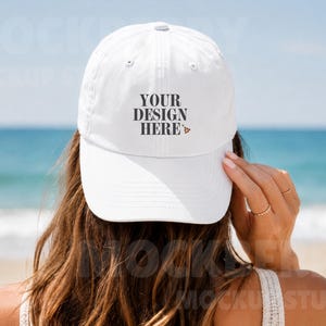 May include: A white baseball cap featuring the black text "YOUR DESIGN HERE" printed on the front center. The cap has a structured crown, a curved brim, and a button on the top. The design includes a small graphic of a pizza slice next to the text.