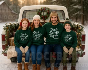 May include: A family of four wearing matching green sweatshirts with the text "Your Design Here" in white, sitting in the back of a vintage truck decorated for Christmas. The truck bed has a wreath and garland.