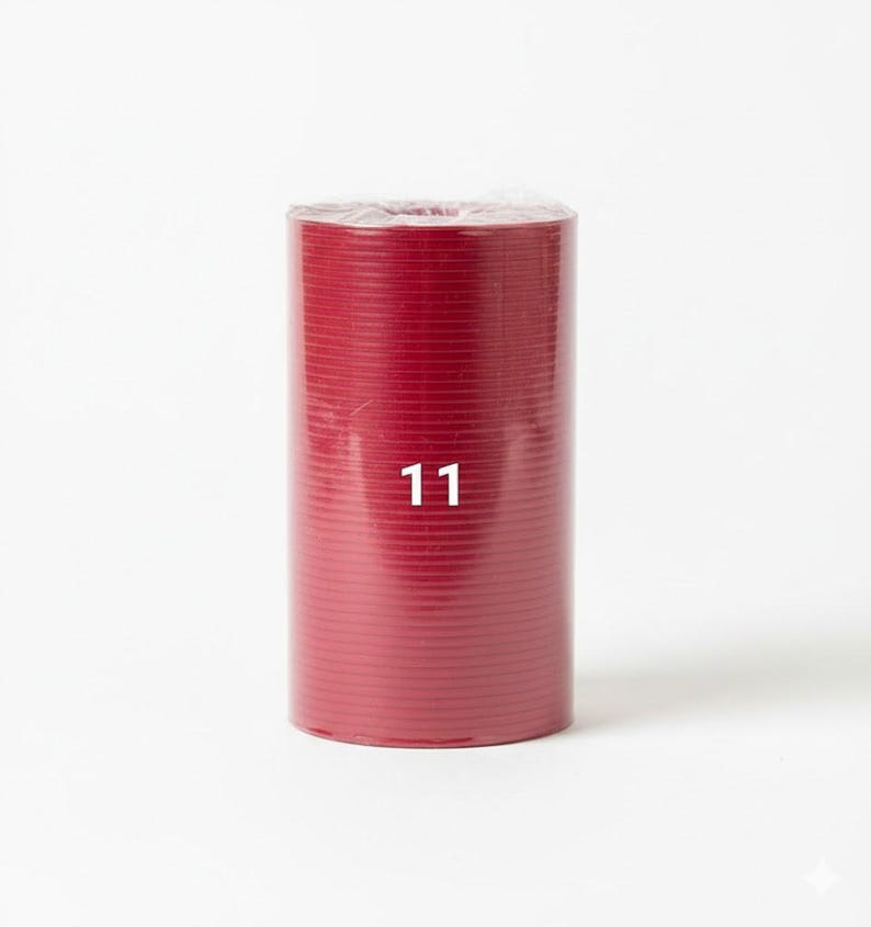 K&ouml;nnte beinhalten: Eine zylindrische Rolle aus tiefrotem Material, verpackt in klarem Kunststoff. Die Zahl "11" ist wei&szlig; auf der Vorderseite der Rolle aufgedruckt. Das Material scheint mit horizontalen Linien strukturiert zu sein.