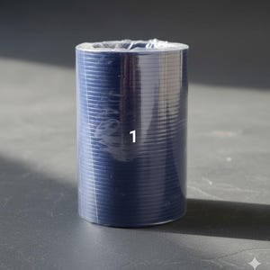 K&ouml;nnte beinhalten: Eine zylindrische Rolle aus marineblauem Material, verpackt in klarem Kunststoff. Die Zahl "1" ist wei&szlig; auf der Vorderseite aufgedruckt. Das Material hat eine gerippte Textur und ist eng gewickelt.
