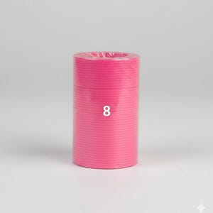 K&ouml;nnte beinhalten: Eine zylindrische Rolle aus leuchtend rosa Material, m&ouml;glicherweise Band oder Kordel, wird vor einem schlichten Hintergrund gezeigt. Die Zahl "8" ist wei&szlig; auf der Vorderseite der Rolle aufgedruckt. Das Material scheint eng gewickelt zu sein.