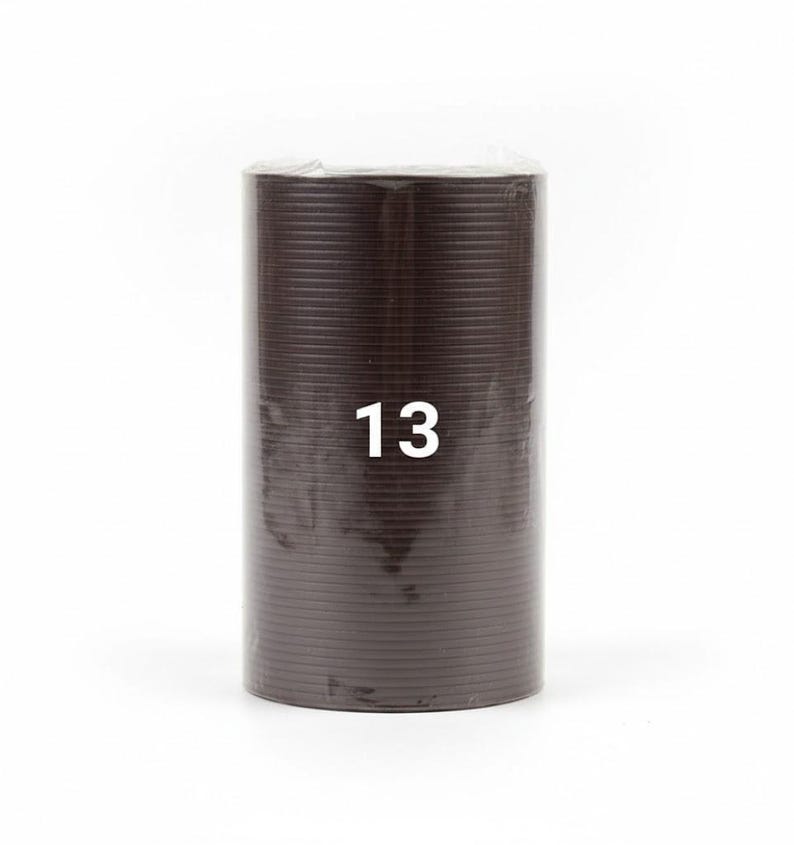 K&ouml;nnte beinhalten: Eine zylindrische Rolle aus braunem Material mit horizontalen Rillen. Die Zahl "13" ist wei&szlig; auf die Vorderseite der Rolle gedruckt. Die Rolle ist in klarem Kunststoff verpackt, und der Hintergrund ist wei&szlig;.