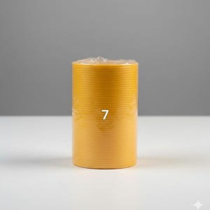 K&ouml;nnte beinhalten: Eine zylindrische, gelbe Kerze mit horizontalen Rillen. Die Zahl "7" ist wei&szlig; auf die Vorderseite der Kerze gedruckt. Die Kerze ist in klarem Kunststoff verpackt und steht auf einer wei&szlig;en Oberfl&auml;che vor grauem Hintergrund.
