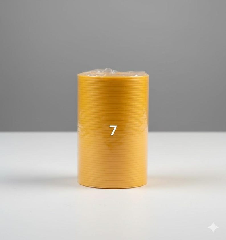 K&ouml;nnte beinhalten: Eine zylindrische, gelbe Kerze mit horizontalen Rillen. Die Zahl "7" ist wei&szlig; auf die Vorderseite der Kerze gedruckt. Die Kerze ist in klarem Kunststoff verpackt und steht auf einer wei&szlig;en Oberfl&auml;che vor grauem Hintergrund.