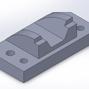 May include: A gray, rectangular mechanical part with a curved top and two circular holes. The part has a stepped design and is likely used in machinery or engineering applications.