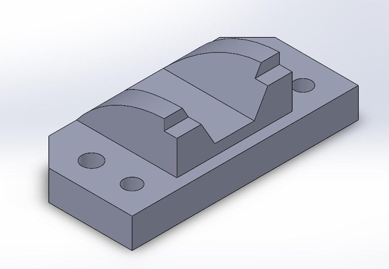May include: A gray, rectangular mechanical part with a curved top and two circular holes. The part has a stepped design and is likely used in machinery or engineering applications.