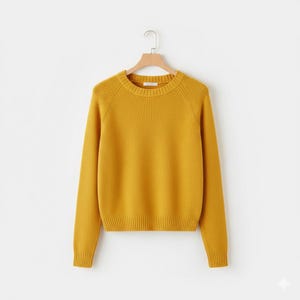 May include: Mustard yellow crew neck sweater with long sleeves. The sweater is made of a soft knit material and hangs on a wooden hanger against a white background. The sweater has ribbed detailing at the cuffs and hem.