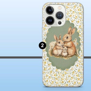 May include: A phone case featuring a watercolor illustration of a bunny family. The design is set against a backdrop of small yellow flowers on a white background. The bunny family is inside a green scalloped frame.