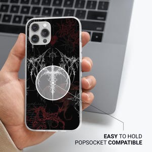 May include: A black phone case with a white and red graphic design. The case has a clear border and is held in a hand. The text "EASY TO HOLD POPSOCKET COMPATIBLE" is visible.