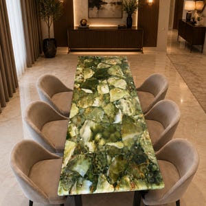 May include: A rectangular dining table featuring a polished green gemstone slab tabletop with a mosaic of varied green and white stone fragments, supported by black metal legs, surrounded by six upholstered light gray curved dining chairs.