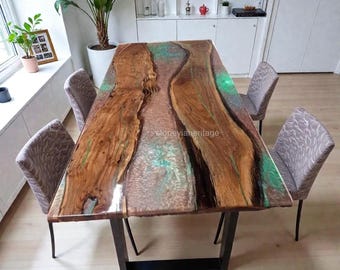 May include: A rectangular wooden dining table with a live edge design, featuring a brown and green epoxy resin river. The table is supported by a black metal base and surrounded by four upholstered chairs. The table measures approximately 72 inches long.