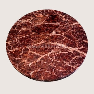 May include: A round, polished tabletop with a rich, reddish-brown hue and intricate white veining. The surface has a natural stone appearance, showcasing a unique pattern. The overall design is circular.