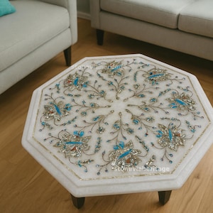 Könnte beinhalten: Ein achteckiger Couchtisch aus weißem Marmor mit einem komplizierten floralen Einlegedesign. Die Oberfläche ist mit Perlmutt- und Türkissteinen verziert, die in einem radialen Muster aus Stielen, Blättern und Blüten angeordnet sind.