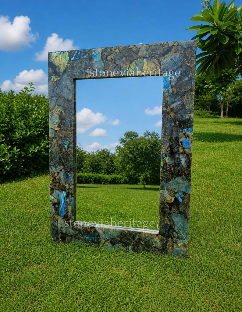 Puede incluir: Un espejo rectangular con un marco de piedra azul oscuro y verde. El marco tiene una apariencia de mosaico con el texto "stoneviaheritage". El espejo est&aacute; sobre un c&eacute;sped con un cielo azul de fondo.