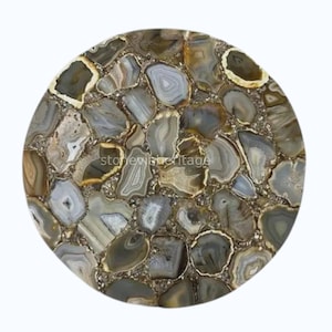 May include: A circular stone slab with a mosaic design. The surface features polished agate stones in grey, brown, and white, set in a light-coloured grout. The stones are of various shapes and sizes, creating a unique pattern.