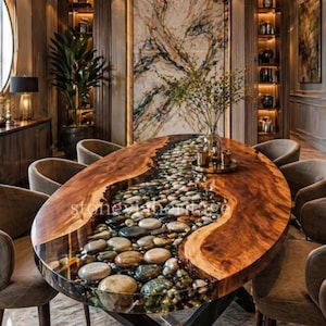 Puede incluir: Mesa de comedor ovalada de madera con un río de piedras incrustadas en resina transparente. La mesa tiene una base de metal oscuro y está rodeada de sillas tapizadas. La habitación tiene un diseño lujoso y moderno.