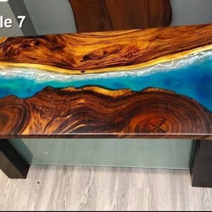 May include: Rectangular wooden table with a unique design. The tabletop features a combination of natural wood and a blue resin that resembles the ocean. The table has dark brown legs and the text "Style 7" in the top left corner.
