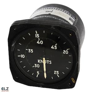 May include: A black aircraft airspeed indicator with a white needle and numbers. The gauge reads in knots, with markings from 5 to 45. The face of the gauge has the text "TE OF KNOTS". The gauge is a vintage aviation instrument.
