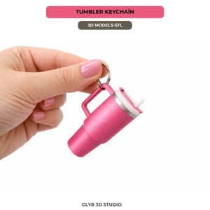 Puede incluir: Un llavero de vaso rosa con asa y pajita blanca. El llavero es de metal y tiene un anillo plateado. El texto "TUMBLER KEYCHAIN" está en la parte superior de la imagen.