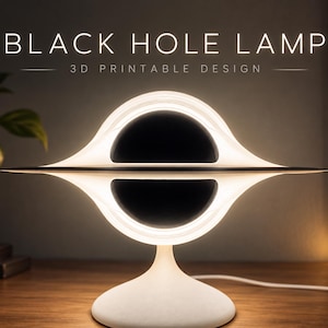 Könnte beinhalten: Eine 3D-druckbare Black Hole Lampe mit einer zentralen schwarzen Kugel, umgeben von einem leuchtend weißen Ring auf einem weißen Sockel. Der Text lautet BLACK HOLE LAMP 3D PRINTABLE DESIGN, STL + STEP FILES und INSTANT DOWNLOAD.