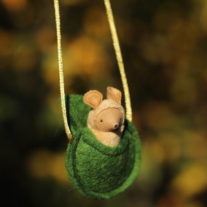 May include: A small, brown, plush mouse is sitting in a green felt pouch hanging from a yellow cord. The pouch is shaped like a leaf and has a drawstring closure.