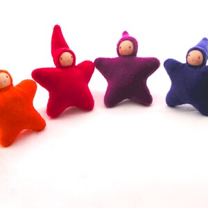 May include: Six felt star-shaped dolls with wooden faces and pointed hats. The dolls are arranged in a rainbow pattern, starting with yellow and ending with green.