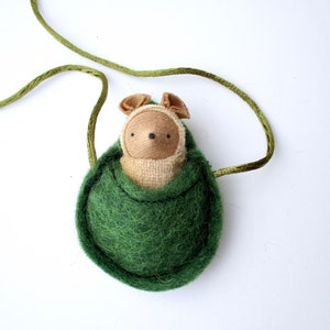 May include: A green felt pouch with a brown felt animal inside. The pouch has a green cord attached to it.