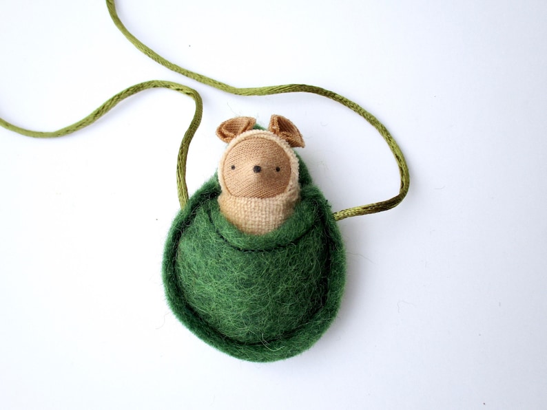 May include: A green felt pouch with a brown felt animal inside. The pouch has a green cord attached to it.