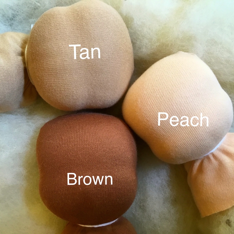Pode incluir: Close-up de cabe&ccedil;as de bonecas nas cores castanho, p&ecirc;ssego e bege. A palavra "Tan" est&aacute; impressa na cabe&ccedil;a bege, "Peach" na cabe&ccedil;a p&ecirc;ssego e "Brown" na cabe&ccedil;a castanha. As cabe&ccedil;as das bonecas s&atilde;o feitas de tecido macio.