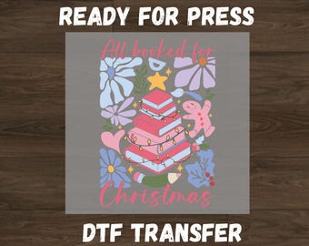 May include: A DTF transfer design with the text "All booked for Christmas." The design features a stack of books decorated as a Christmas tree, surrounded by flowers, a gingerbread man, and a star.