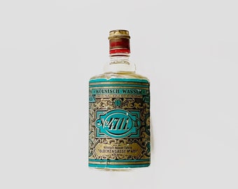 May include: A clear glass bottle of cologne with a gold and blue label. The label reads "KÖLNISCH WASSER FABRIK "GLOCKENGASSE N°4711" KÖLN".