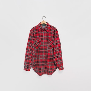 May include: A red and black plaid long-sleeve shirt with two chest pockets, hanging on a wooden hanger. The shirt has a button-down front and a collar. The plaid pattern is a classic design.