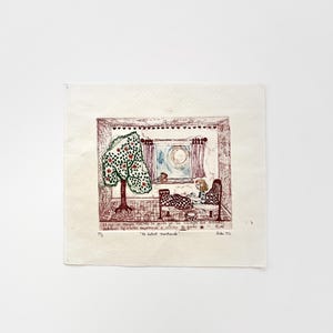 May include: A framed print depicting a whimsical interior scene. A person sits at a table near a window, with a tree outside. The print is in shades of red, green, and brown, with text at the bottom.