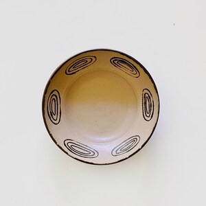May include: A beige ceramic bowl with a brown rim and a black swirl design around the edge.