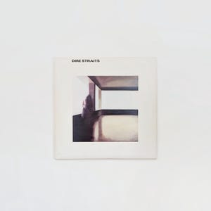 May include: A square album cover for the band Dire Straits. The cover features an abstract image of a person in a room with a window. The band's name is printed in black at the top.