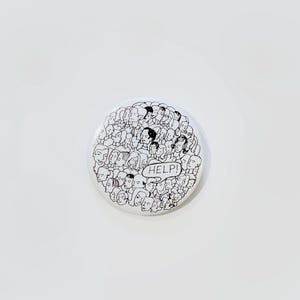 May include: A white button with a black and white illustration of many faces. A speech bubble with the word "HELP!" is in the center of the button. The button is round and has a glossy finish.