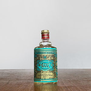 Puede incluir: Una peque&ntilde;a botella de vidrio transparente de colonia 4711. La botella tiene una etiqueta dorada con el texto "K&Ouml;LNISCH WASSER" y "GLOCKENGASSE N&deg;4711 K&Ouml;LN".