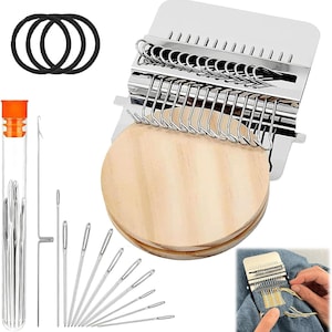 May include: A silver metal weaving loom with a wooden base, needles, and black hair ties. The loom has a series of hooks for holding yarn. A clear tube contains several needles. The loom is shown in use on a piece of denim.